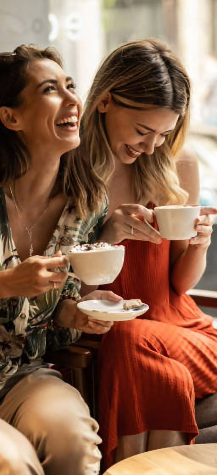Friends laughing and sharing coffees — keeping the Good Vibes flowing